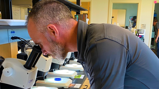 A two-part image shows a researcher using a microscope in a lab, and a presenter standing before a bar graph. Text overlay: "4 years ago... We were already doing this".